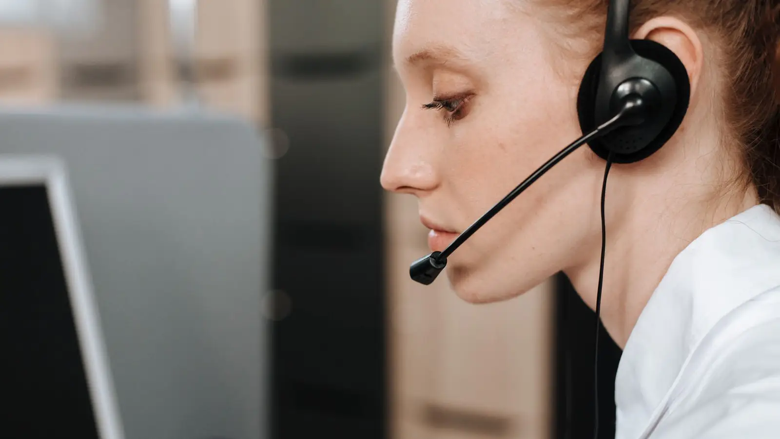 Mitarbeiterin mit Headset am Bildschirmarbeitsplatz im Profil